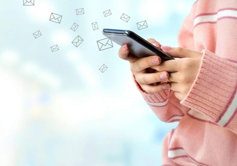 close-up-young-female-hand-in-pink-sweater-using-smartphone-sending-emails-with-blurred-interior_t20_Yw7G9m