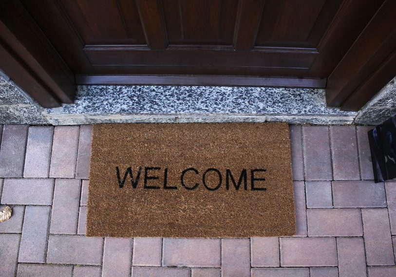 Welcome mat on a brick flooring by front door